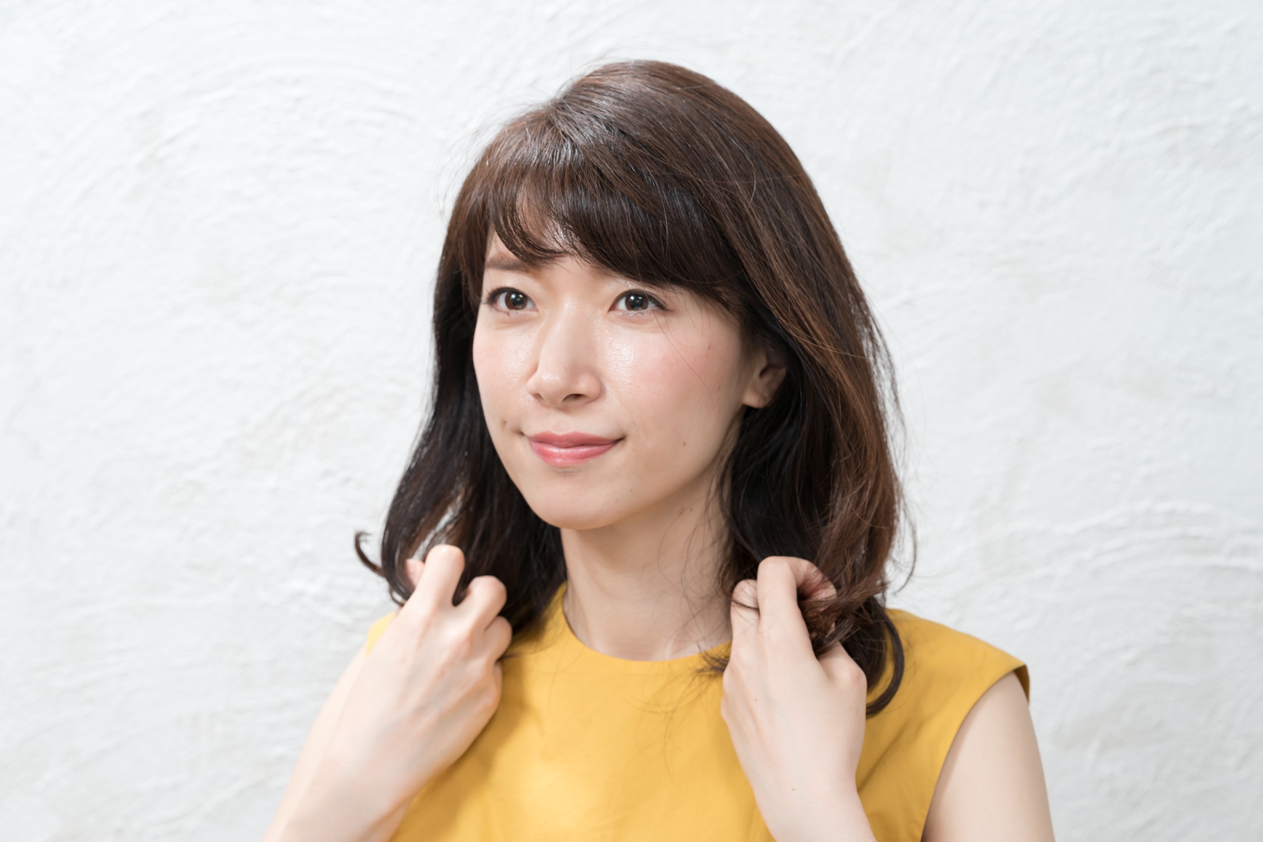パール粒ひと粒大のワンクスを両手のひらになじませて、毛先の内側からもみ込む。このひと手間で毛束にまとまりと動きが出ます。