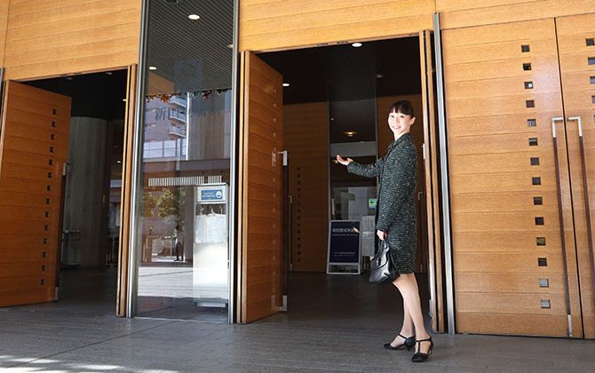 新国立競技場のメインエントランスの扉前に立つ、プリンシパルの米沢 唯さん。
