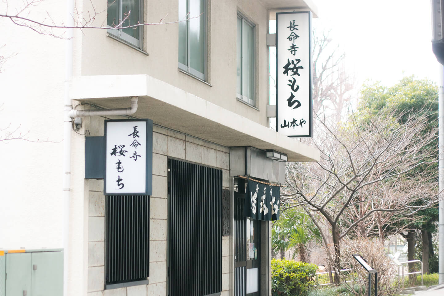 「長命寺桜もち」店舗の外観。看板には筆文字で店名が書かれ、入り口には紺色ののれんがかかっている