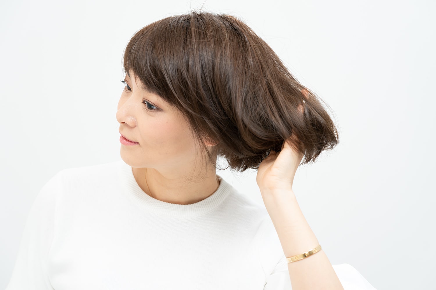パール粒ひと粒大のワックスを手のひらに伸ばして、髪の内側の中間から毛先にかけて毛束を左右へ振るようにつける。逆サイド、後頭部も同様に。