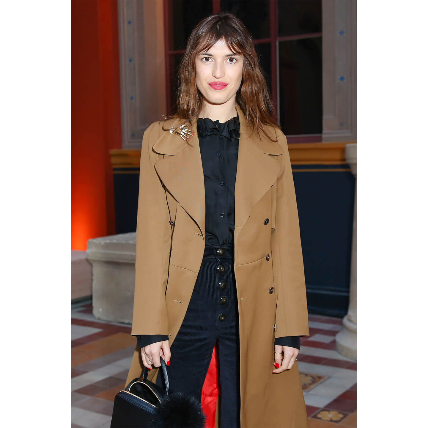 人の手がモチーフのブローチをつけるJeanne Damas(ジャンヌ・ダマス)