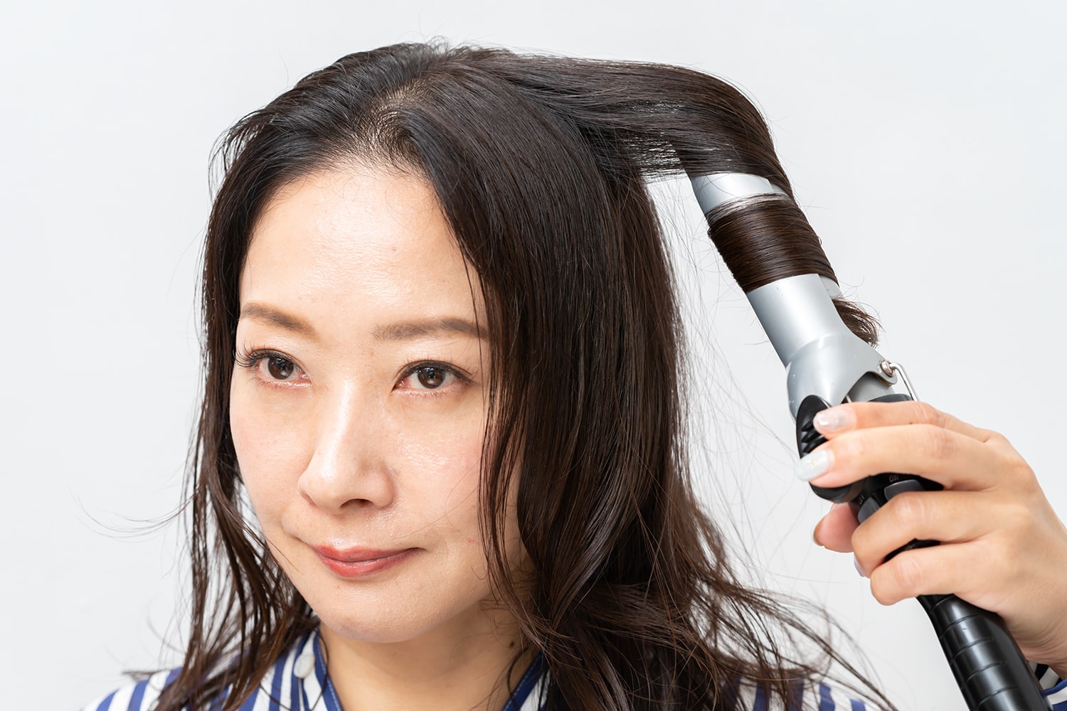 同じくカールアイロンに毛束を斜めに巻き付けること。
