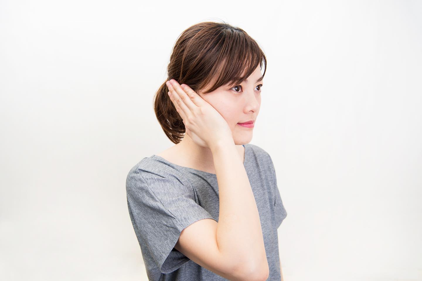 手を軽く丸めて、耳全体を覆うように当てている
