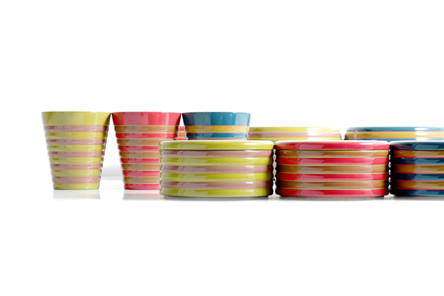 漆塗りのコップと蓋つきの器が並ぶ。鮮やかな色付けとベージュをこうごに塗り、独楽模様を表現している