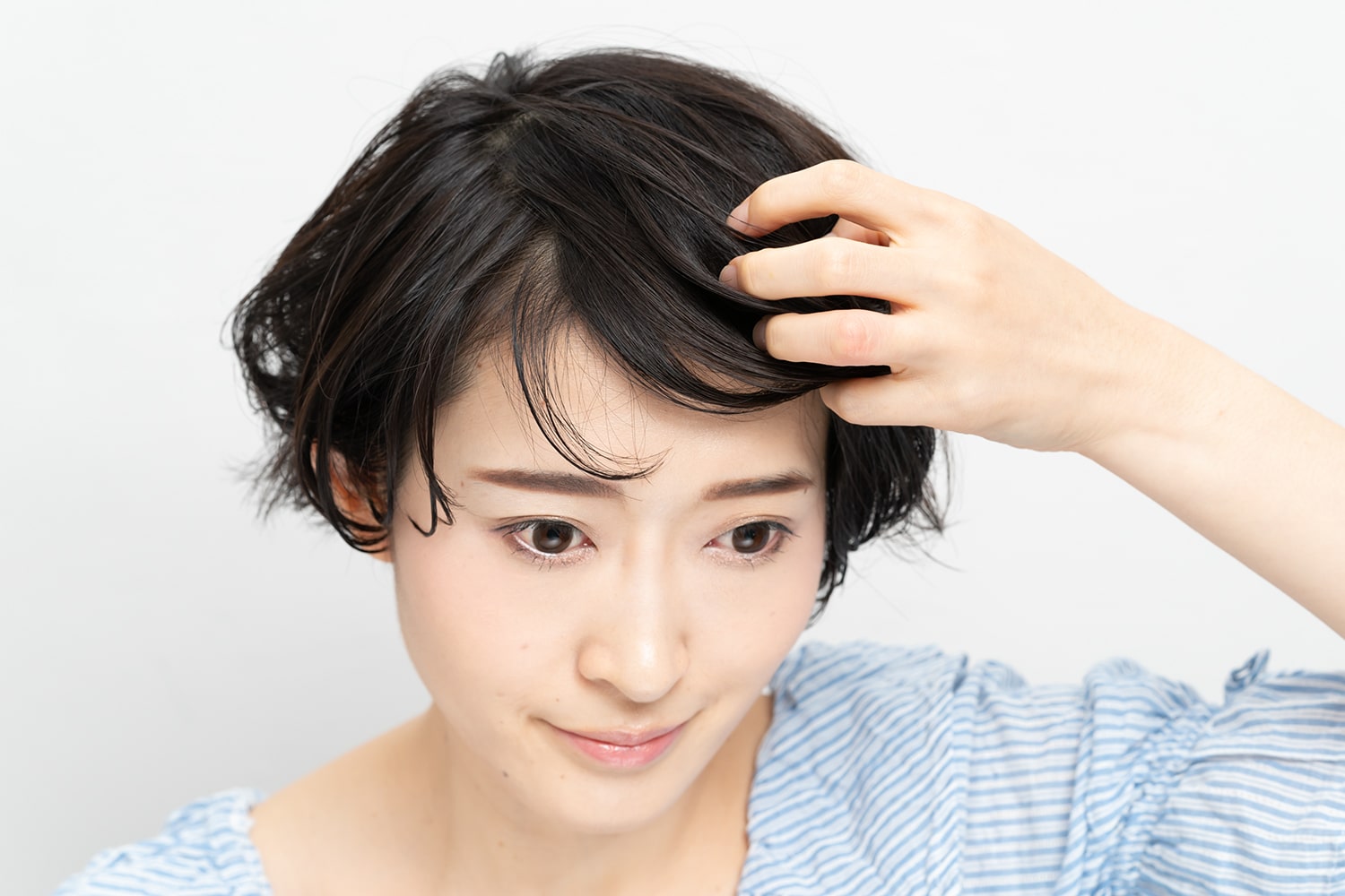 前髪に厚みを持たせるように頭頂部から前方向に手ぐしで形を整える。