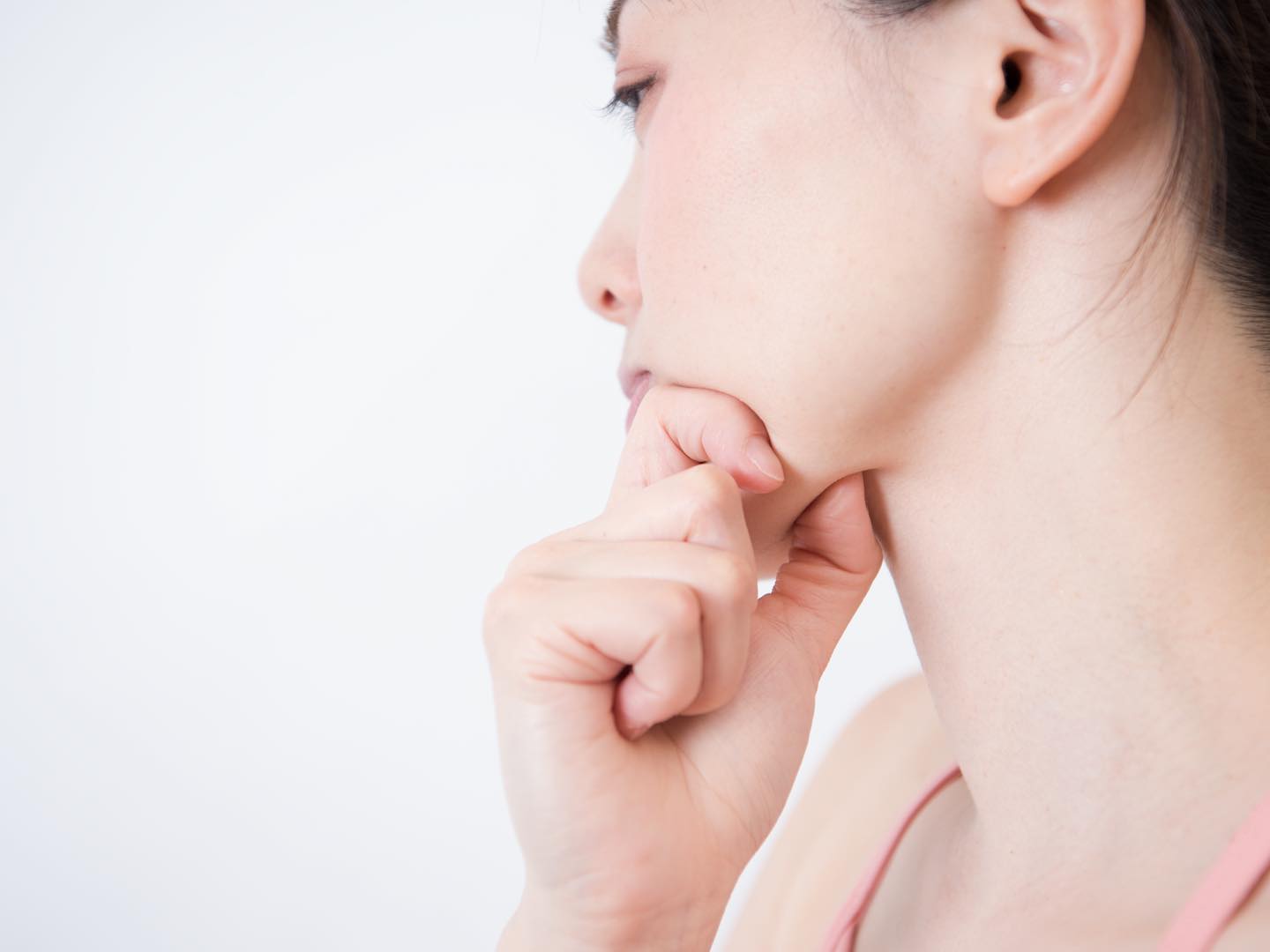 指であごを挟み、マッサージしている女性