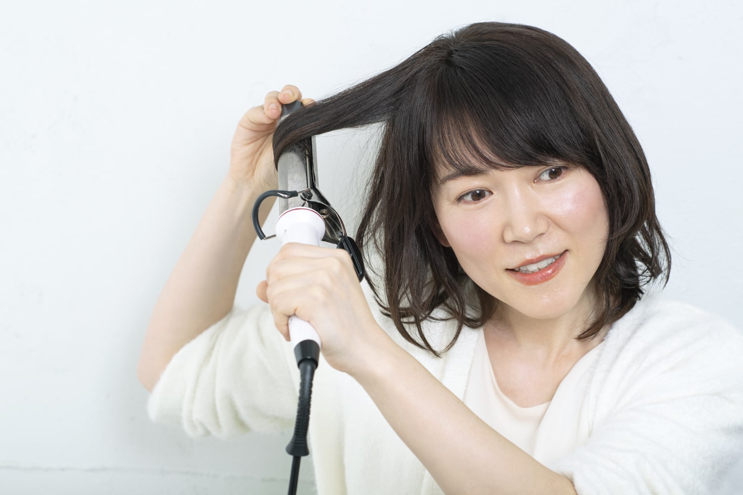 32mmのヘアアイロンで、毛先にワンカールをつけるように、2~3段に分けて巻く。