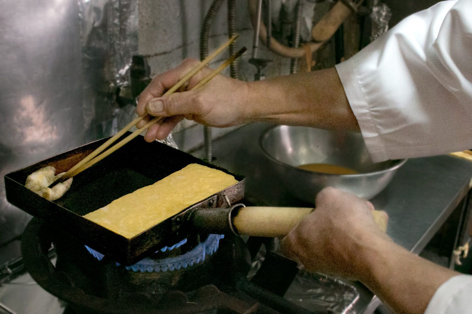 奥から手前に1/2の幅で巻き、玉子焼きを玉子焼き器の側面にそろえて横も焼きます。また、奥にも2~3回で油を敷き直します