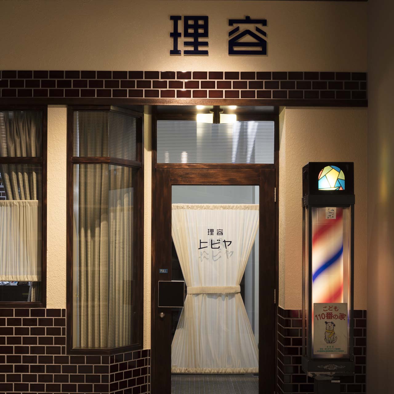 「理容 ヒビヤ」のドア周辺。昭和にタイムスリップしたかのような雰囲気だ。