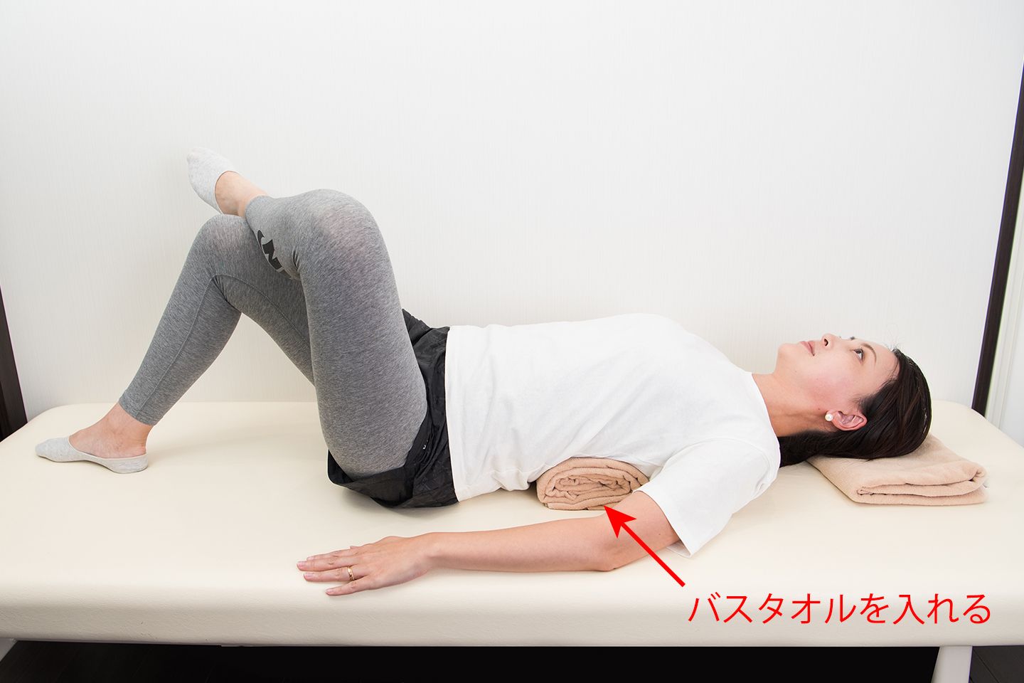 仰向けになって寝ている女性。左足首を右足の膝にかけている