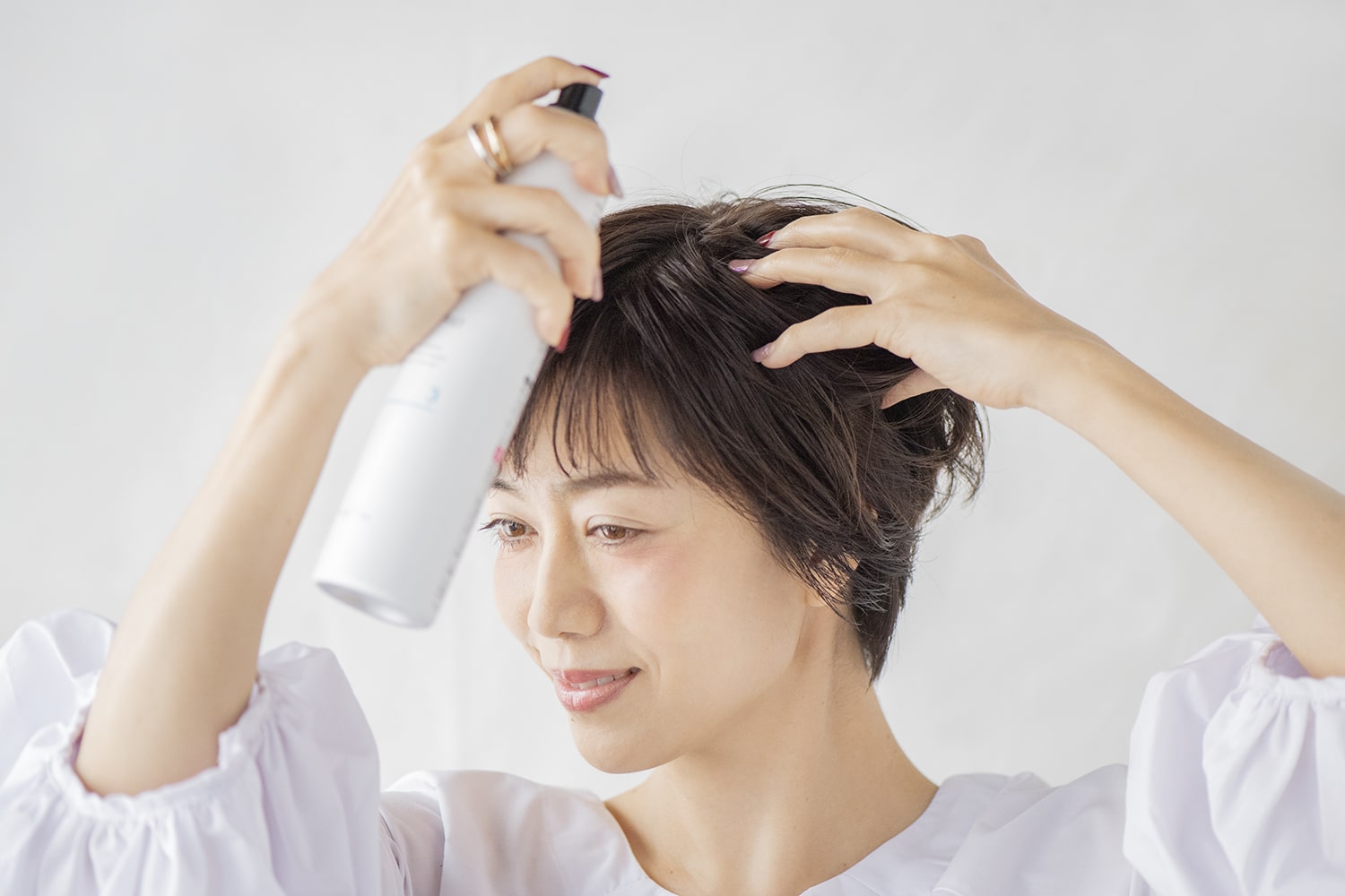 ナチュラルハードタイプのヘアスプレーを、髪に手ぐしを通しながらスプレー。