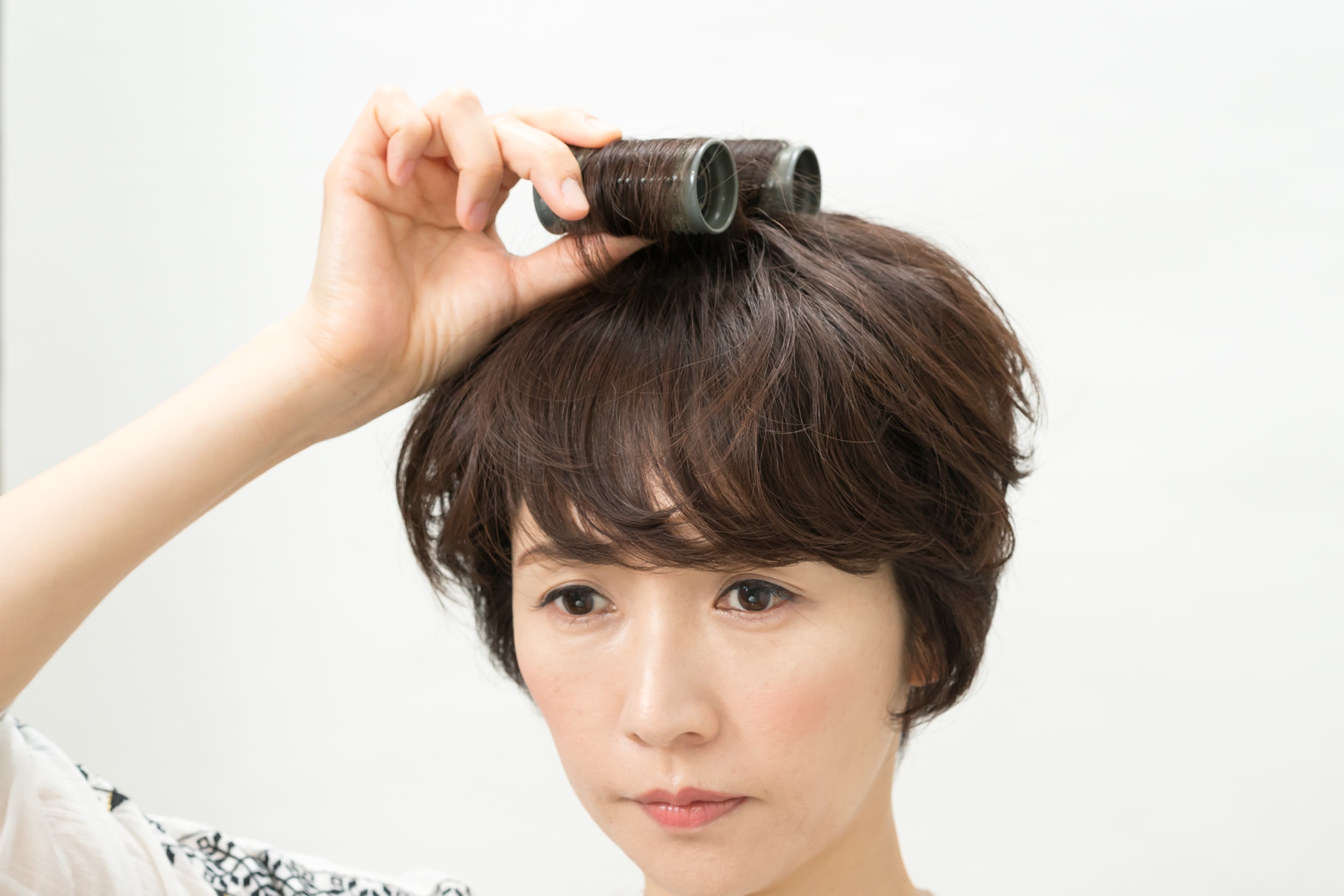 カーラーは直径3㎝くらいのものを使用。つむじ前の毛束をふたつに分けて、後ろの毛束は後方に巻き、前の毛束は前方に向けて巻きつける。