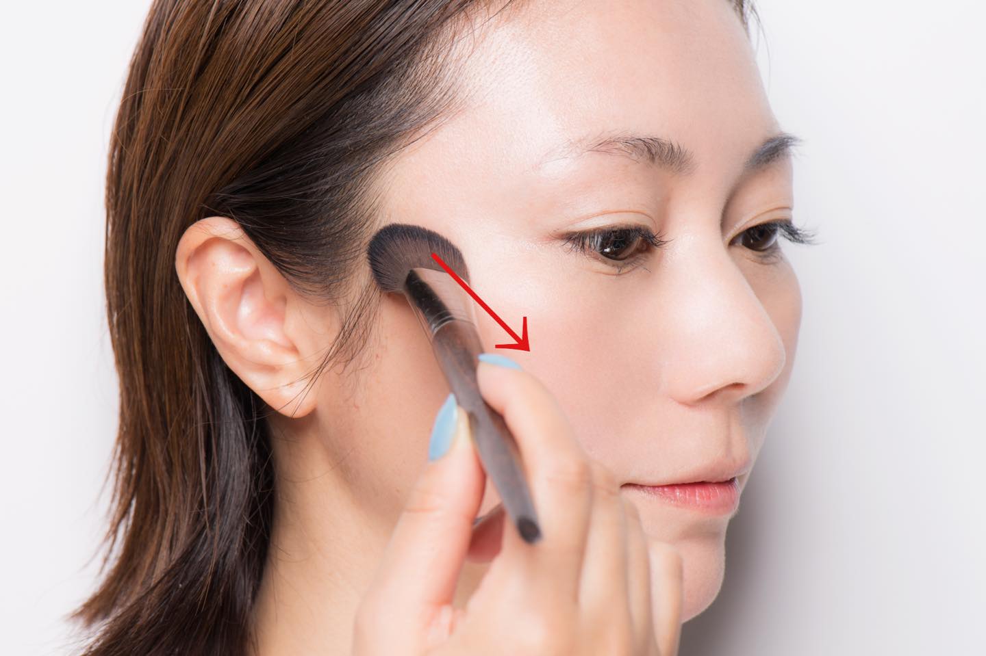 肌にのせる前に、チークをとったブラシを一度手の甲でならし、余分な粉を落としておく。