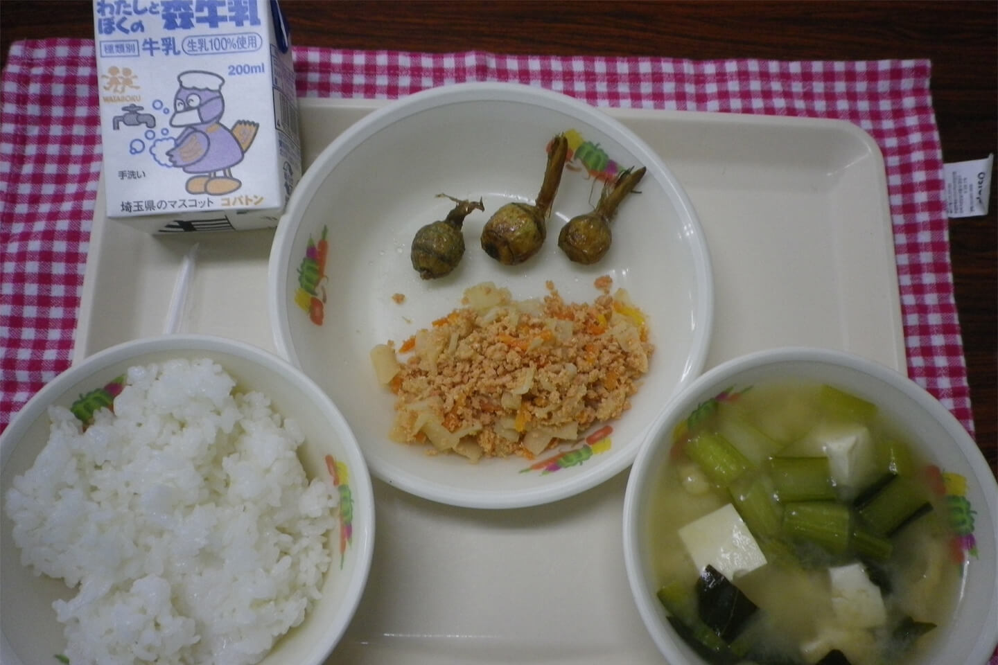 お盆の上に、ご飯、汁物、おかずのお皿と牛乳が並び、おかずのお皿には小ぶりな素揚げしたくわいが3つ並んでいる