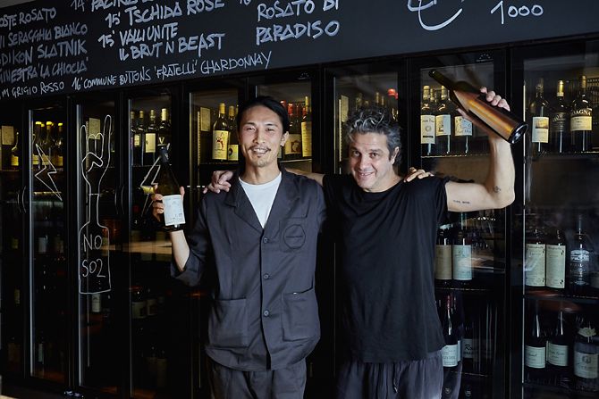 左から東京店ヘッドソムリエのソン・ユガン氏、本店オーナーのジョバンニ・パラディソ氏。手にしたのはそれぞれのお気に入りワイン。「旨みたっぷりで、ナチュラルワインになじみのない方にもおすすめ」とソン氏が言うのはイタリアの微発泡ワイン(ブリュット&ビースト/ヴァッリ ウニーテ¥6,200)。「大切な友達が作っている、大好きなワイン。何度も現地に行ったことがあるよ」とジョバンニ氏が語るのは、シチリアのワイナリーによる希少なワイン(ファニーノ/ガブリオ ビー二¥20,000) ※ワインは共にボトルのみ。グラス提供なし