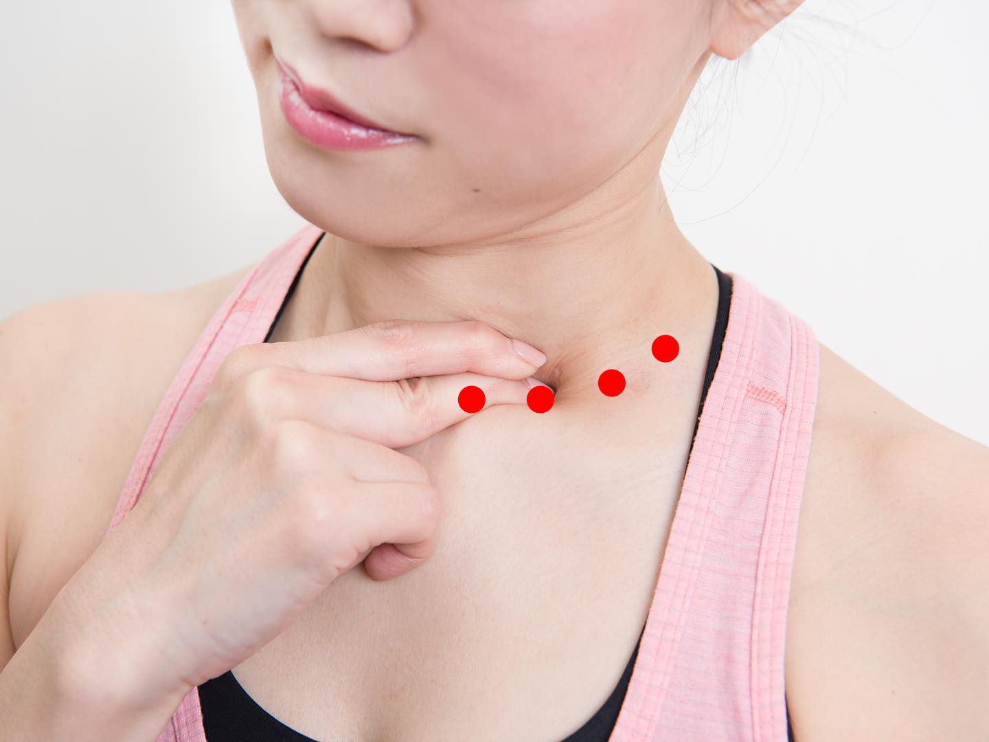 鎖骨の手前を指でプッシュしている女性