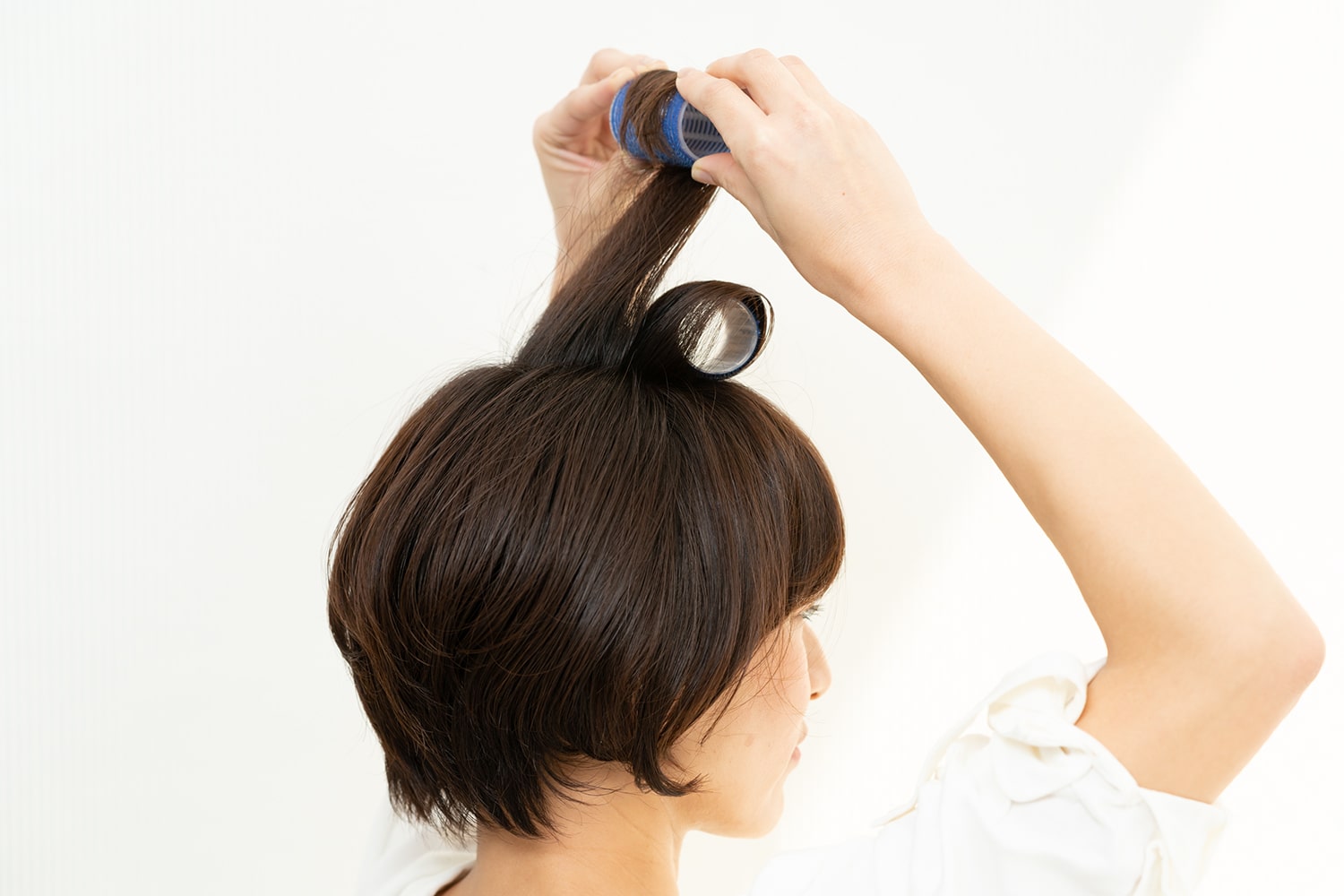 頭頂部の髪を前後2つに分け、前側は前向きに、後ろは後ろ向きにカーラーで毛先から巻く。