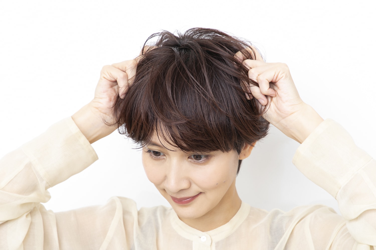 手のひらにグロスジェルをのばし、トップについた立ち上がりと毛先のカールを全体になじませながら動きをつけて整える。