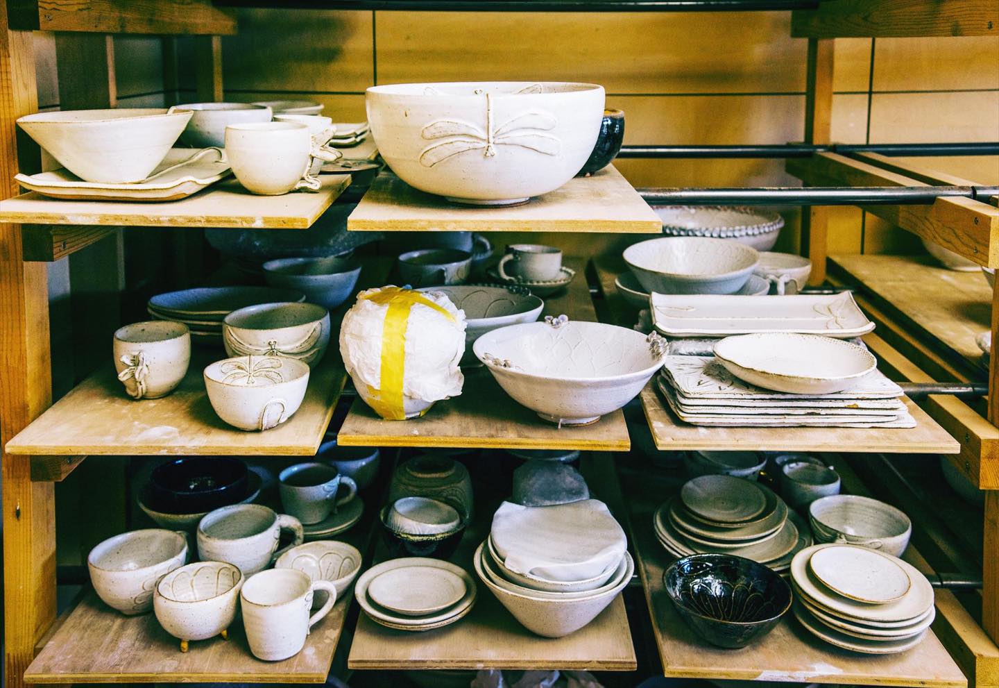 陶房内には作品がずらり。完成までには最低でも2か月かかります。手板にのせた器を運ぶ力仕事もお手のもの。