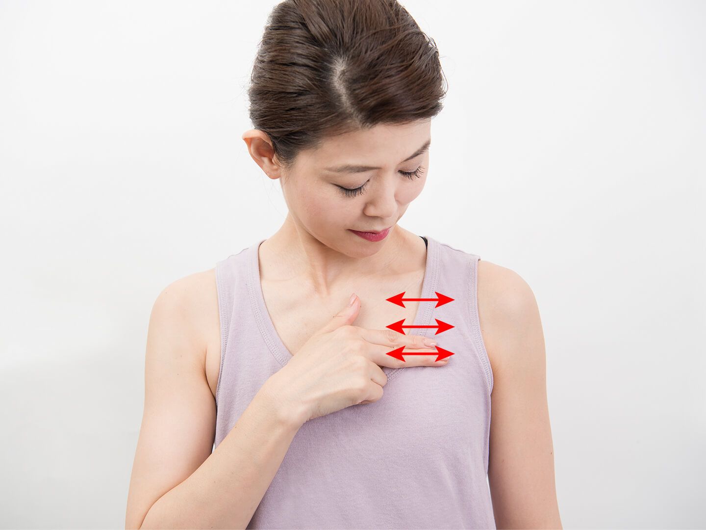 人さし指と中指で胸元をマッサージしている女性