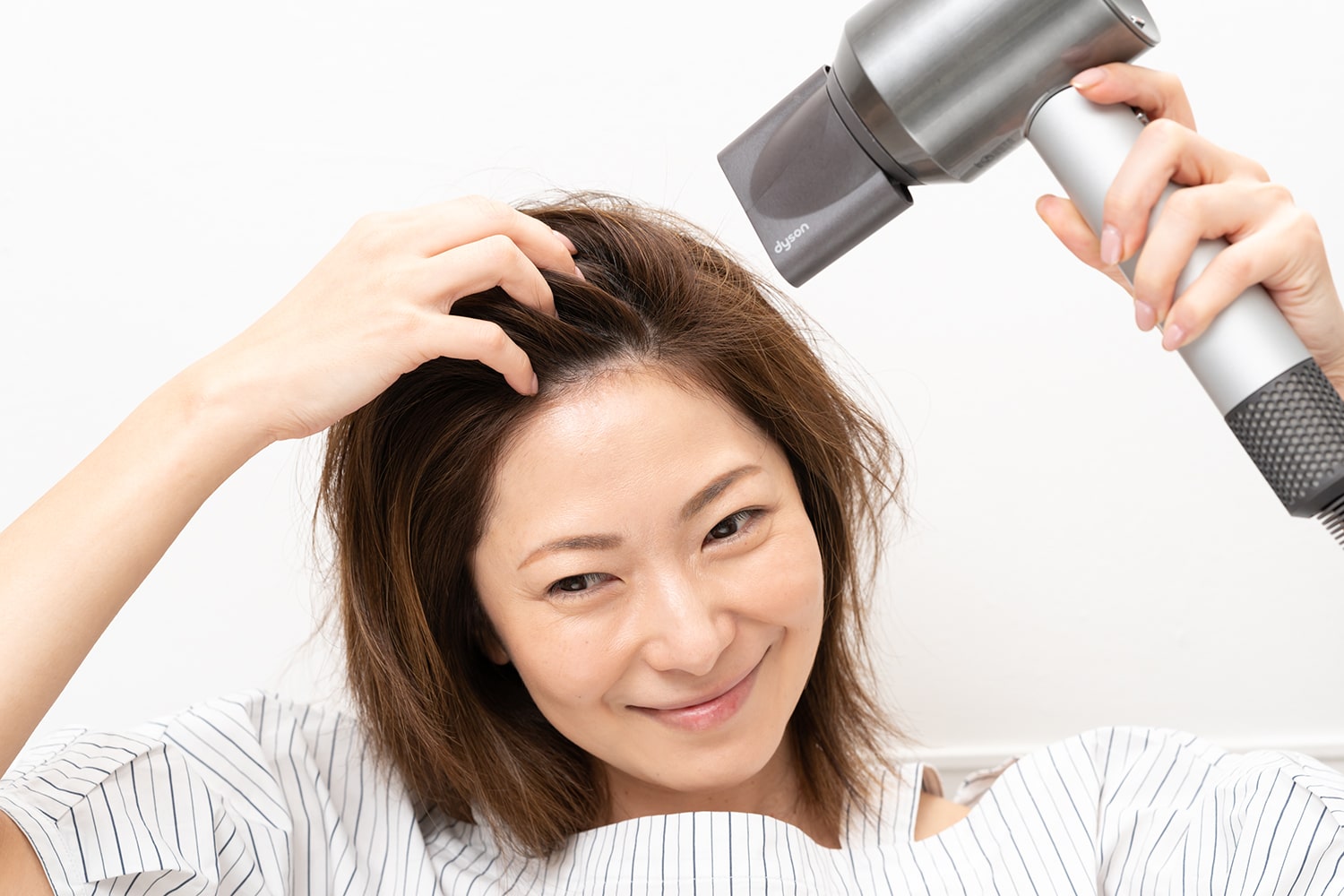 分け目とは逆方向にドライヤーをあてることで、頭頂部にふんわりとした立ち上がりが生まれる。