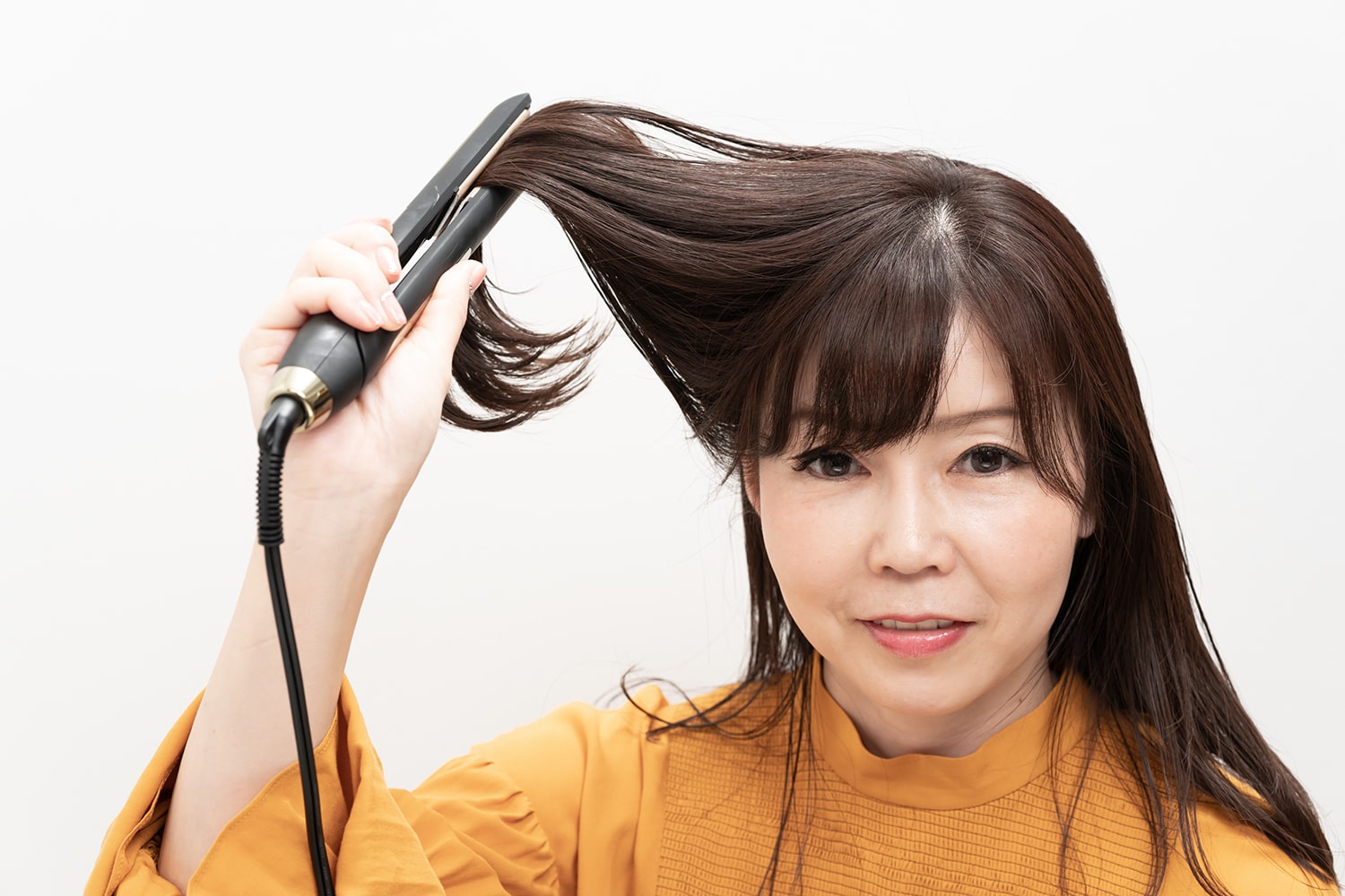 ストレートアイロンで毛束の中間を挟み、持ち上げるように上に引き抜くのがコツ。毛先の重みで丸みのある自然なカールに。
