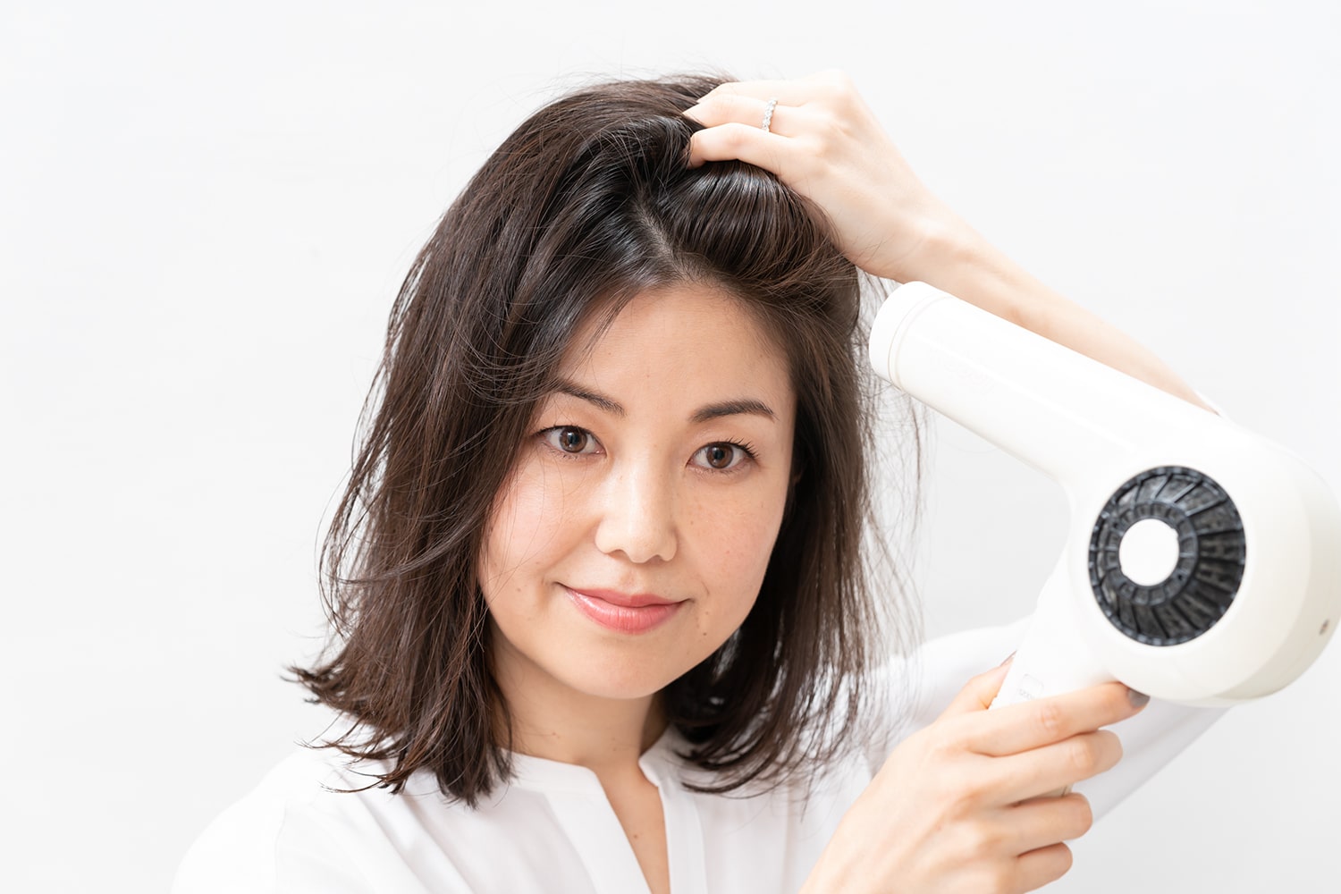 いつもの分け目とは逆方向から、分け目をまたぐように毛ぐしでとかしながらドライヤーをあてる。